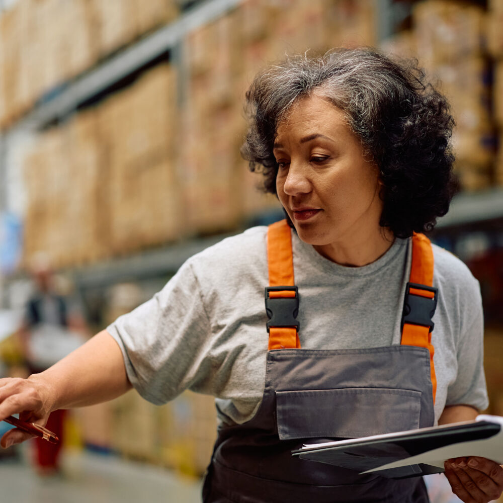 Mature female worker checking inventory at distribution warehouse.