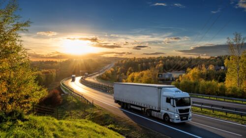 White,Trucks,Driving,On,The,Highway,Winding,Through,Forested,Landscape