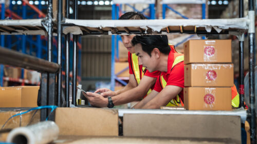 Warehouse worker checking details stock product and scanning a barcode on box package in the background warehouse., Industrial and industrial concept.